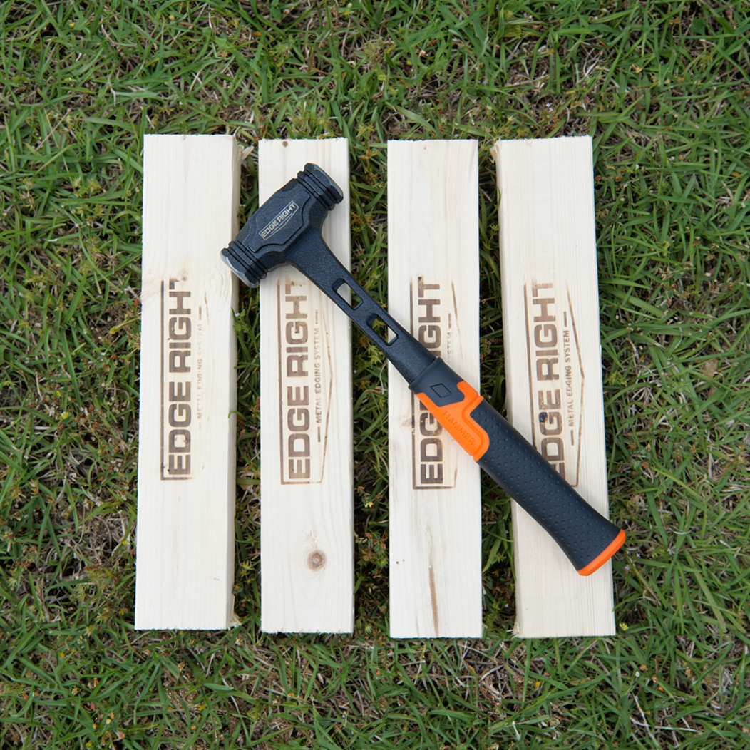 Edge Right Installation Kit with hammer and four branded wood blocks on grass.