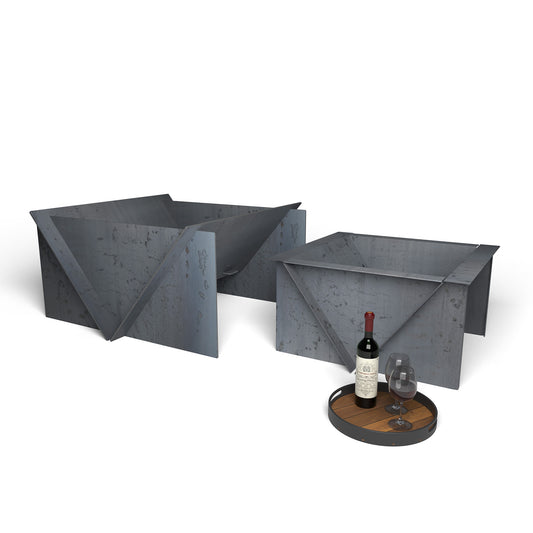 Modern steel fire pit set with precision built design, displayed with a bottle and glasses on a tray in front.
